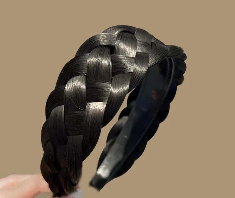 Braided hair extension held by a hand with a brown background